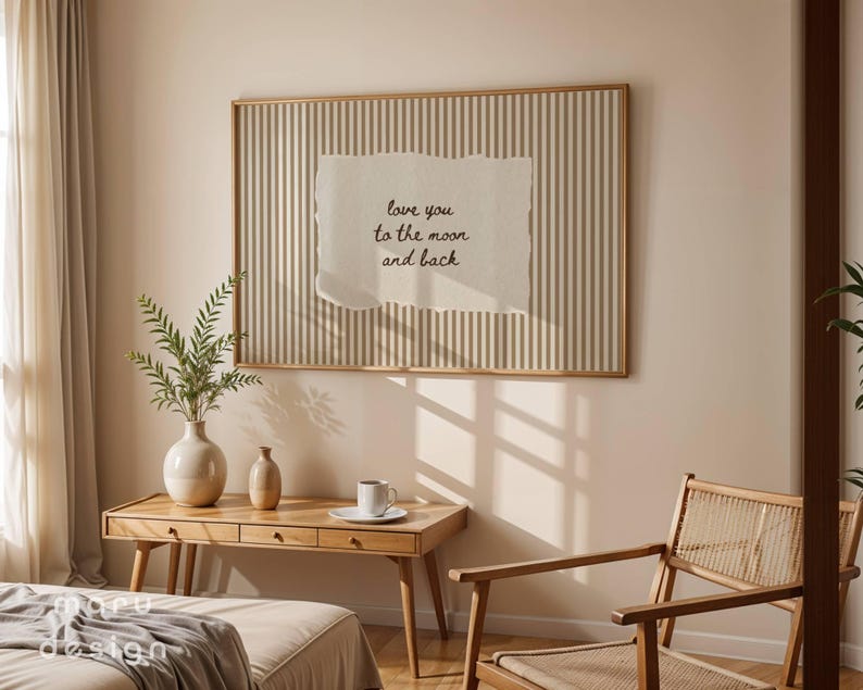 May include: A framed artwork with a vertical striped background and a torn paper element. The paper has the text "love you to the moon and back" in black script. The room also features a wooden desk, chair, and decorative vases.