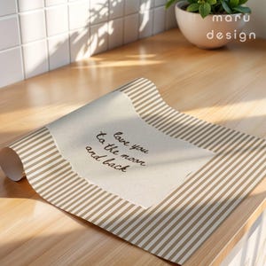 May include: A roll of paper with a tan and white striped pattern. The paper has a torn edge with the handwritten text "love you to the moon and back". The maru design logo is in the upper right corner.