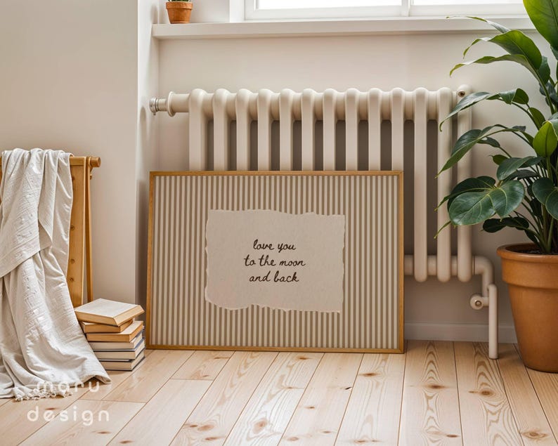 May include: A framed print with a vertical striped background and a torn paper insert. The insert features the text "love you to the moon and back" in a handwritten style. The frame is light brown, and the print is displayed indoors.