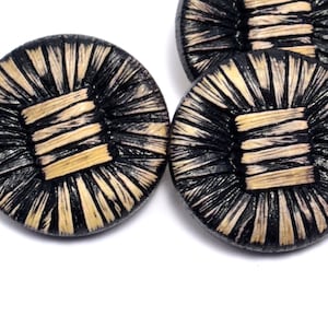 May include: Four black and beige woven buttons with a square design in the center.