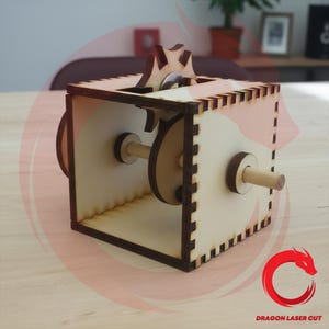 Könnte beinhalten: Eine Holz-Puzzlebox mit einem Zahnradmechanismus. Die Box ist aus hellem Holz mit dunkleren braunen Kanten und Akzenten gefertigt. Das Design umfasst sichtbare Zahnräder und Holzdübel, die die inneren Funktionen des Puzzles zeigen.