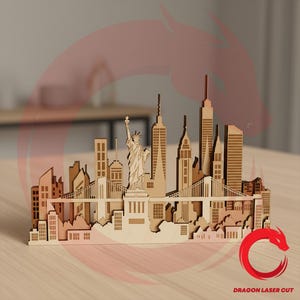 Pode incluir: Uma maquete de madeira cortada a laser do horizonte de Nova York, com a Estátua da Liberdade, pontes e arranha-céus. O horizonte é feito de madeira castanha clara, mostrando detalhes arquitetônicos. O texto "DRAGON LASER CUT" é visível.
