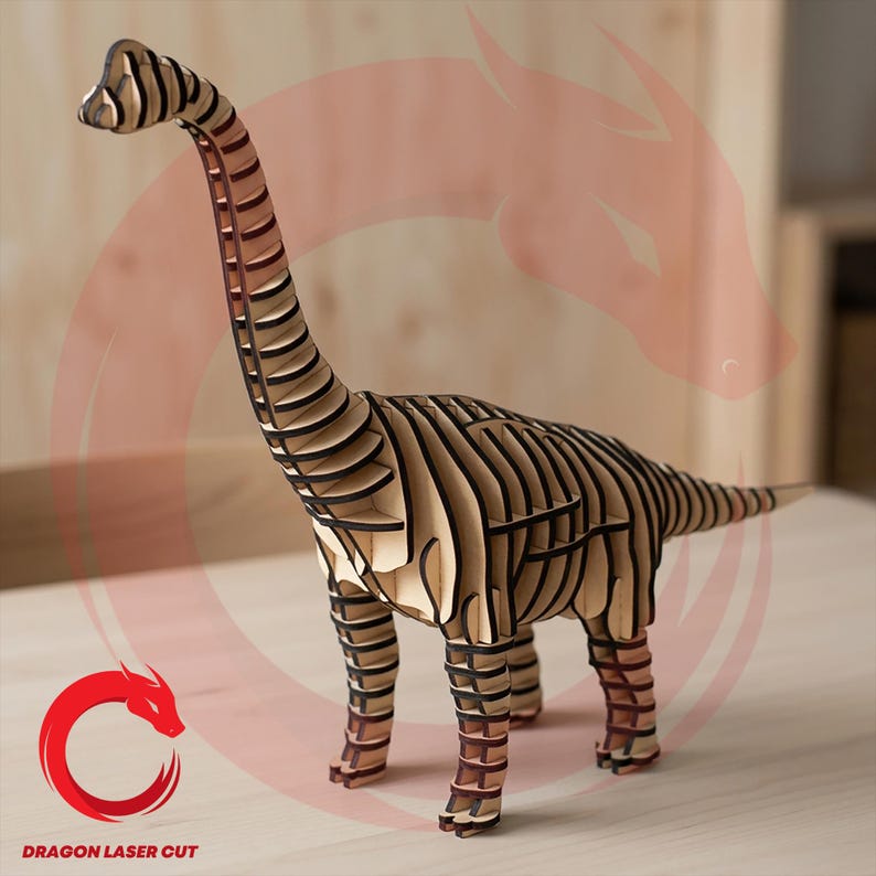 May include: A wooden Brachiosaurus dinosaur model with a long neck and tail. The model is made of layered wood pieces, with dark brown edges and light brown surfaces. The dinosaur is standing on a light-coloured surface. The logo "DRAGON LASER CUT" is visible.