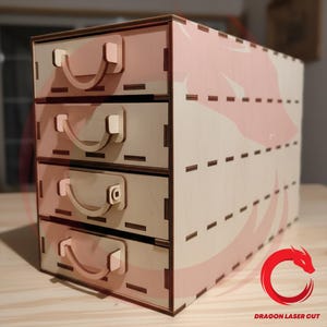 Puede incluir: Una caja de almacenamiento de madera de cuatro cajones con asas curvas. La caja está hecha de madera de color claro con un diseño cortado con láser en los lados. El logotipo de Dragon Laser Cut es visible en la esquina inferior derecha.