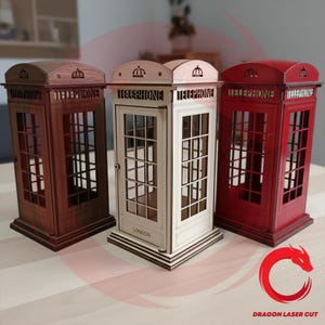 Könnte beinhalten: Drei Holzmodelle von Telefonzellen in den Farben Dunkelbraun, Off-White und Rot. Jede Zelle trägt das Wort "TELEPHONE" und eine Tür mit Fenstern. Auf der off-white Zelle steht "LONDON".