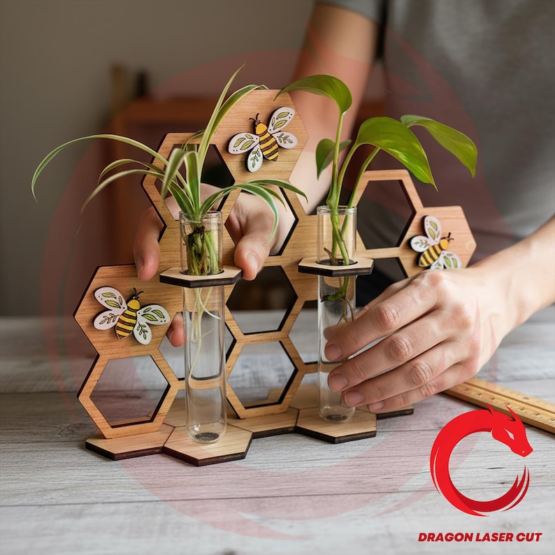 May include: Wooden honeycomb-shaped plant holder with three clear glass test tubes for displaying small plants. The holder features decorative bee cutouts and is made of light-colored wood. The plants have green leaves and are in water.