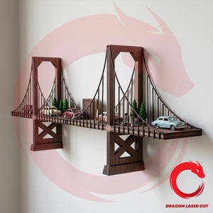 Puede incluir: Estantería de madera marrón oscuro con forma del puente Golden Gate. Cuenta con coches, árboles y figuras en miniatura. La estantería está montada en una pared blanca. La longitud de la estantería es de unos 60 cm.