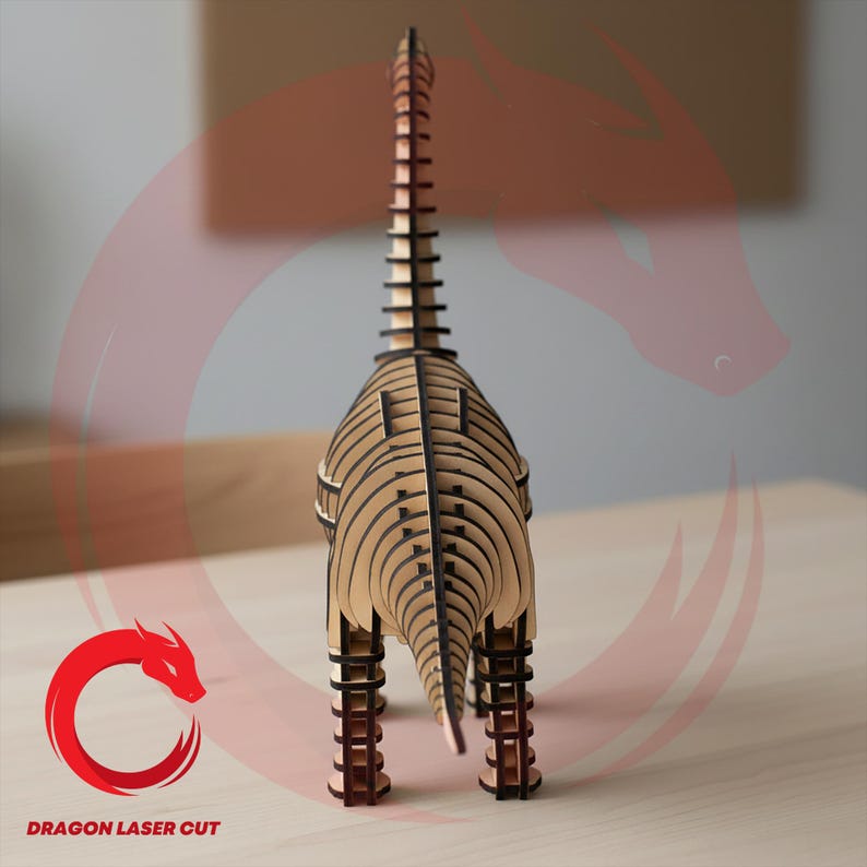 May include: A laser-cut wooden dinosaur model, assembled from multiple layers. The dinosaur is light brown with dark brown detailing, with a long neck and tail. The model stands on four legs. The text "DRAGON LASER CUT" is visible.
