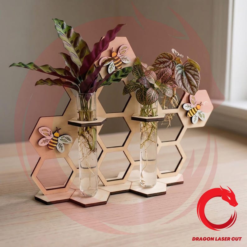 May include: A wooden honeycomb-shaped plant holder with three glass test tubes, each holding a small plant. The holder features decorative wooden bees and is made of light-colored wood. The plants have green and burgundy leaves.