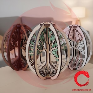 May include: Three wooden, spherical sculptures with tree designs. The sculptures are in shades of brown, beige, and white, with intricate cut-out tree and root patterns. One has green leaves. The sculptures are on a light-colored surface.