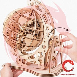May include: A wooden globe puzzle with intricate laser-cut details. The globe features a skeletal design, showcasing the continents. The puzzle includes gears and a base, all crafted from light-colored wood. The design is complex and appears to be a DIY project.