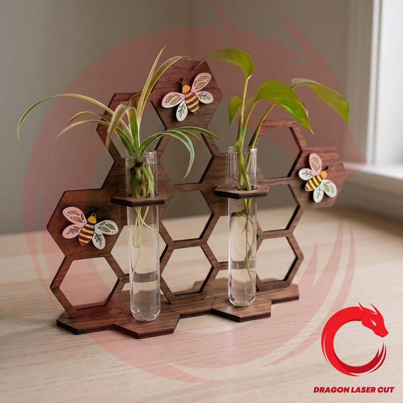 May include: A wooden honeycomb-shaped plant holder with three clear glass test tubes, each holding a small plant. Decorative wooden bees are attached to the honeycomb. The wood is a dark brown color.