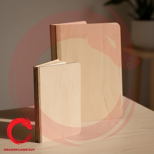 以下が含まれることがあります： さまざまなサイズの3つの木製ノートが、丸みを帯びた角で、明るい色の木製の表面に表示されています。 ノートは明るい色の木材でできており、最も小さいノートのページがわずかに見えます。 テキスト「DRAGON LASER CUT」が左下に表示されています。