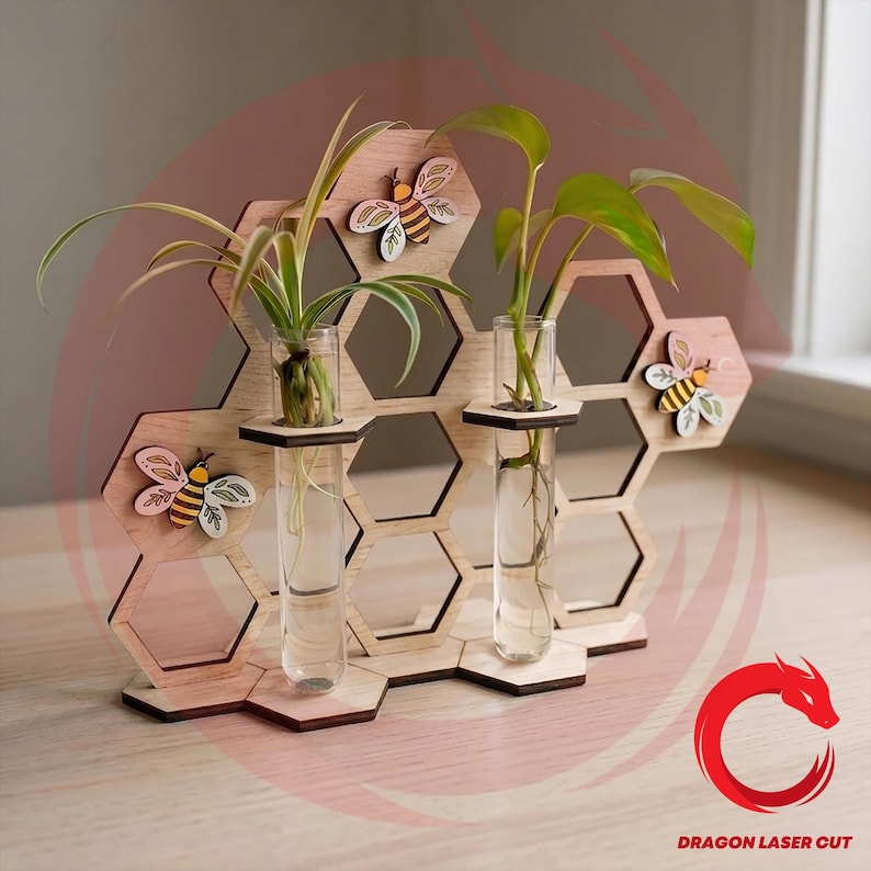 May include: Wooden honeycomb-shaped plant holder with three clear glass test tubes for propagating plants. The holder features decorative wooden bees and is designed to hold small plants. The natural wood color contrasts with the green plants.
