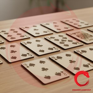 May include: A set of rectangular playing cards crafted from light-colored wood, featuring laser-engraved suit symbols and numbers in black. The cards display various spade and club patterns. A red dragon logo and the text DRAGON LASER CUT appear.