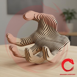 May include: A wooden sculpture of a hand, crafted from layered wood pieces. The sculpture is light brown with dark brown lines, creating a striped effect. The hand is in an open position, with fingers slightly curved. The logo "DRAGON LASER CUT" is in the bottom right corner.
