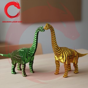 May include: Two wooden dinosaur sculptures, one green and one gold, stand facing each other. The green dinosaur is on the left, and the gold dinosaur is on the right. The text "DRAGON LASER CUT" is in the upper left corner.