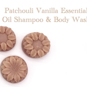 May include: Three round, light brown soap bars with a moulded sunflower design on top. The text "Patchouli Vanilla Essential Oil Shampoo & Body Wash" is printed in a light brown serif font above the soap bars on a plain white background.