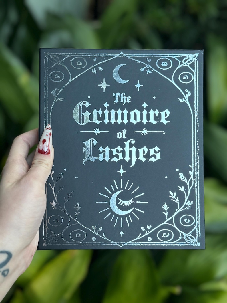 Black Grimoire of Lashes lash book held in hand, gothic packaging for dramatic gothic lashes and individual lash clusters.