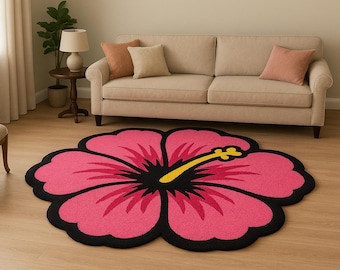 May include: A pink, flower-shaped rug with a black border and a yellow and black centre. The rug is placed on a light wood floor in front of a beige sofa. The rug's design resembles a hibiscus flower.