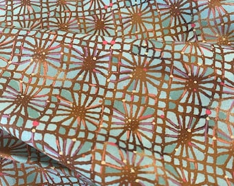 May include: A fabric featuring a repeating geometric pattern of brown grid lines overlaid on a light blue background. The design includes stylized starburst or floral motifs in brown, accented with small dots of pink and white throughout.
