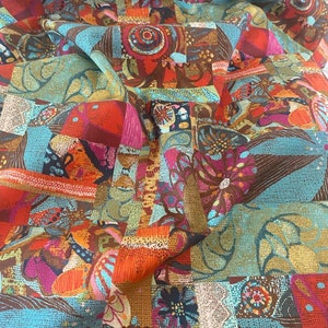 May include: A vibrant fabric with a patchwork design. The pattern features squares and rectangles in shades of orange, teal, brown, and pink. Floral and abstract motifs are incorporated throughout the design, creating a colorful and textured appearance.