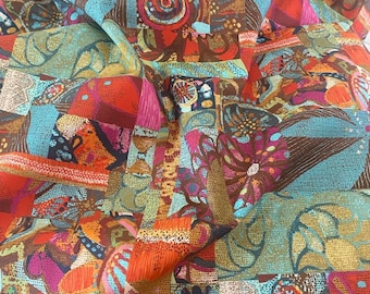 May include: A vibrant fabric with a patchwork design. The pattern features squares and rectangles in shades of orange, teal, brown, and pink. Floral and abstract motifs are incorporated throughout the design, creating a colorful and textured appearance.