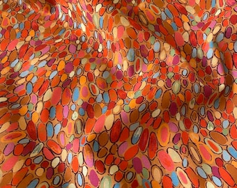 May include: Close-up of a fabric with an abstract pattern of colorful ovals. The ovals are in shades of red, orange, blue, purple, and yellow, with black outlines, set against a tan background. The fabric is slightly wrinkled.