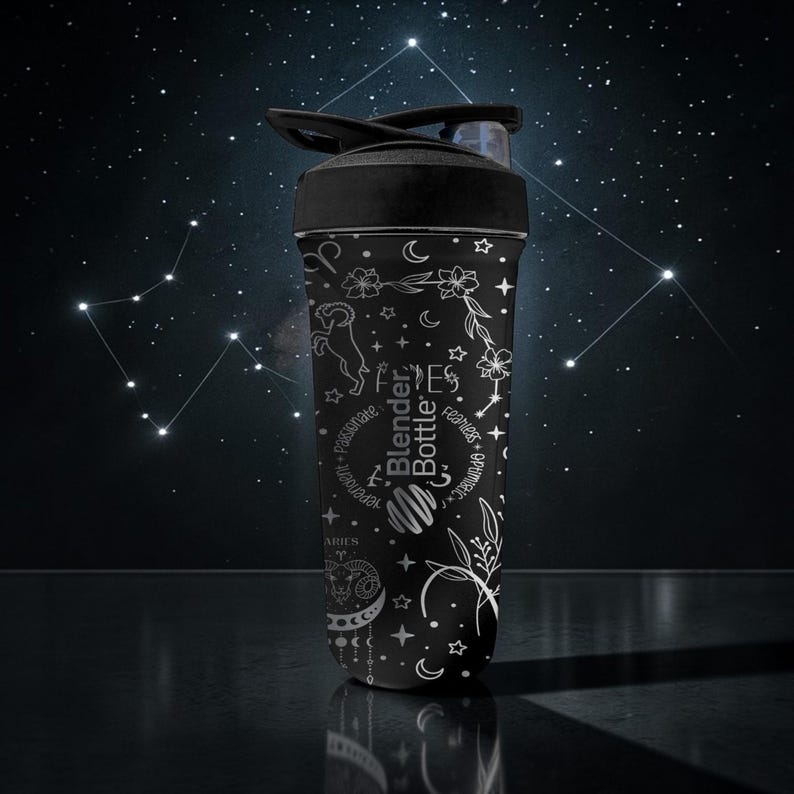Pode incluir: Garrafa Blender Bottle preta com desenhos celestiais e florais brancos. A garrafa apresenta o texto "Blender Bottle" e o s&iacute;mbolo do zod&iacute;aco de &Aacute;ries. A tampa &eacute; preta e tem um fecho flip-top. O fundo &eacute; um c&eacute;u noturno escuro com constela&ccedil;&otilde;es.