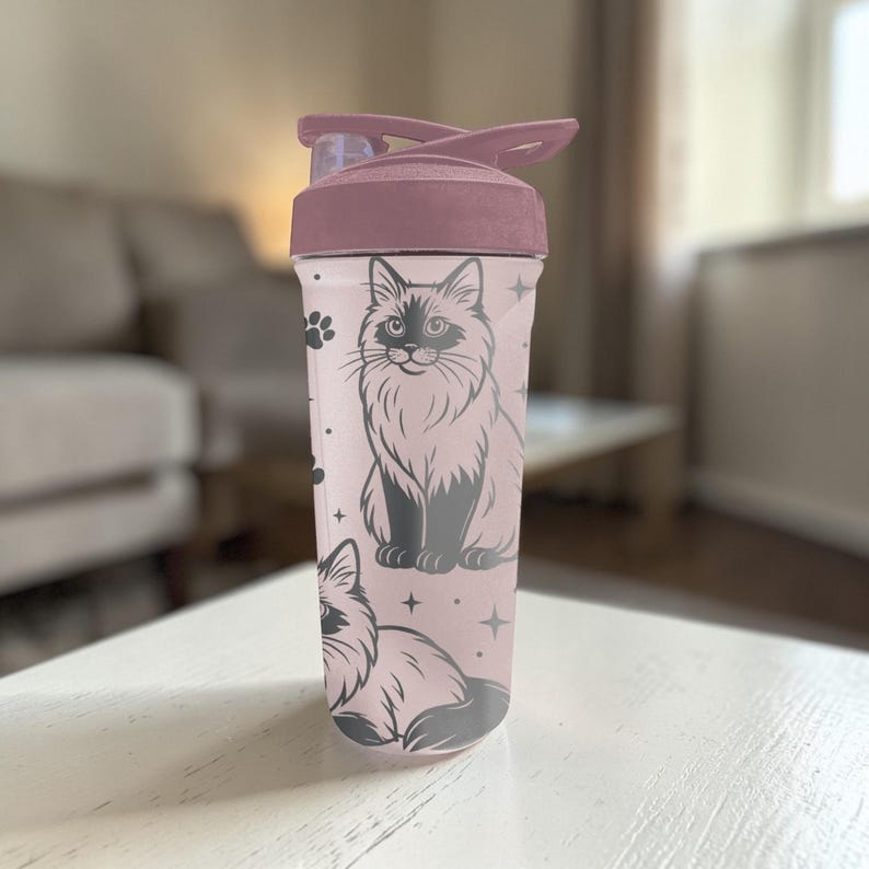 May include: A pink water bottle with a flip-top lid and a black cat illustration. The cat is depicted in a detailed, stylized drawing. The bottle also features paw prints and star accents.