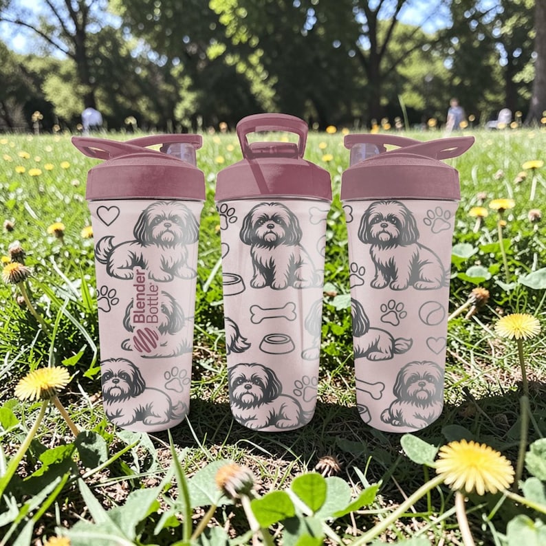 May include: Three pink Blender Bottles with a Shih Tzu dog pattern. Each bottle has a flip-top lid and a handle. The bottles are decorated with dog illustrations, paw prints, and bone shapes.