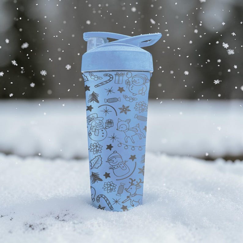 Puede incluir: Una botella de agua azul claro con tapa abatible, decorada con un dise&ntilde;o de vacaciones de invierno. El dise&ntilde;o incluye copos de nieve, mu&ntilde;ecos de nieve, renos y bastones de caramelo. La botella est&aacute; en un entorno nevado.