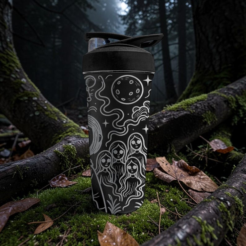 May include: Black water bottle with a white illustration of celestial bodies and figures. The design includes a moon, stars, and a group of women. The bottle has a black lid and is set against a forest backdrop.