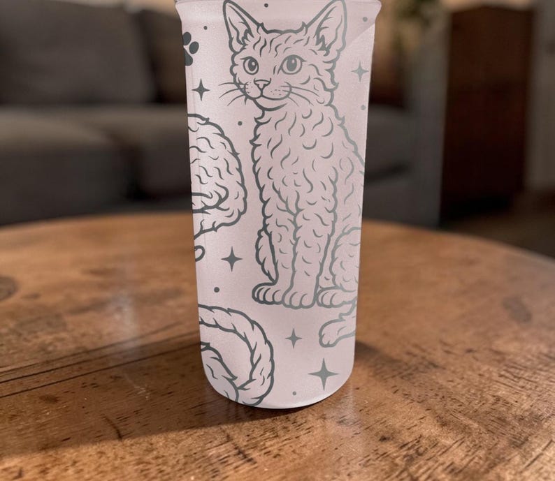 May include: A light pink tumbler with a cat illustration, brain, and rope design. The cat is sitting, and the design is in a light gray color. The tumbler has a straight shape and is made of a translucent material.