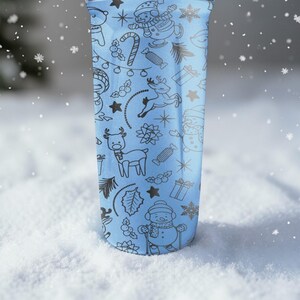 Puede incluir: Un vaso azul claro con un patr&oacute;n negro repetido de ilustraciones tem&aacute;ticas navide&ntilde;as, que incluyen mu&ntilde;ecos de nieve, renos y bastones de caramelo. El vaso est&aacute; sobre un fondo nevado, con copos de nieve cayendo.