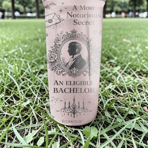 Pode incluir: Uma vela rosa com o texto "A Most Notorious Secret" e "An Eligible Bachelor". A vela apresenta uma silhueta de um homem numa moldura decorativa. A palavra "Rumour" est&aacute; impressa na parte inferior da vela.