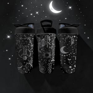 Pode incluir: Tr&ecirc;s garrafas Blender Bottle pretas com desenhos celestes brancos, incluindo estrelas, luas e s&iacute;mbolos do zod&iacute;aco. Uma garrafa apresenta a palavra "ARIES". As garrafas t&ecirc;m tampas pretas e est&atilde;o sobre um fundo escuro com uma lua crescente e estrelas.