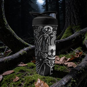 May include: Black Blender Bottle with a white graphic design featuring a character from a movie. The bottle has a black lid with a flip-top opening. The text "Blender Bottle" is printed on the side.
