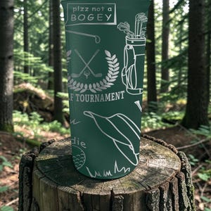 May include: A green golf-themed tumbler with white illustrations of golf clubs, a golf bag, and a golf ball. The text "plzz not a BOGEY" is at the top, and "F TOURNAMENT" is printed below a golf-themed emblem.