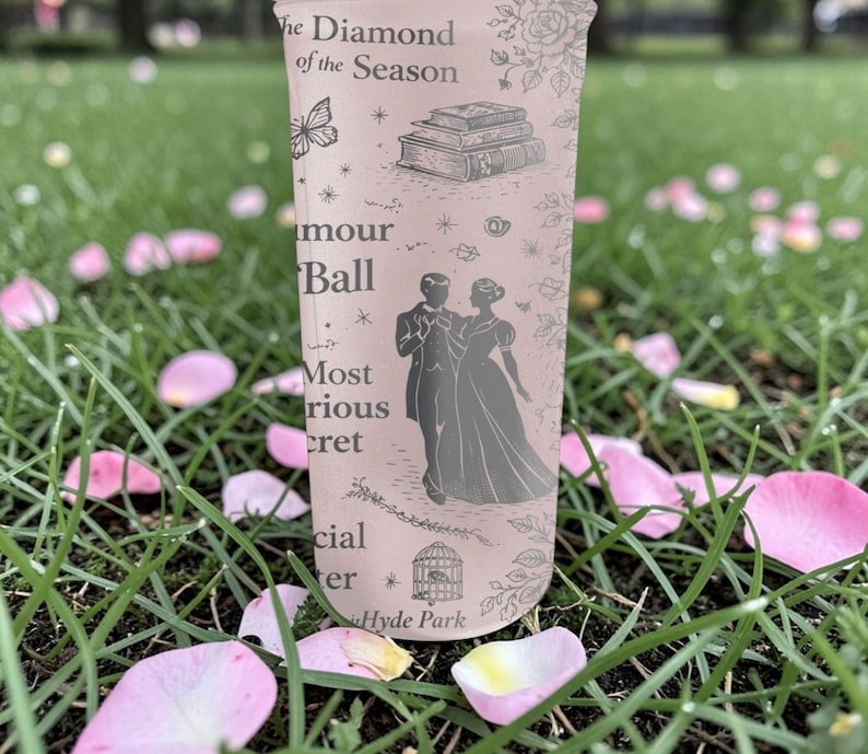 Pode incluir: Um copo alto e claro com texto e ilustra&ccedil;&otilde;es, incluindo um casal, livros e uma borboleta. O texto inclui "The Diamond of the Season", "amour Ball" e "Hyde Park". O copo &eacute; cercado por grama verde e p&eacute;talas de flores cor-de-rosa.