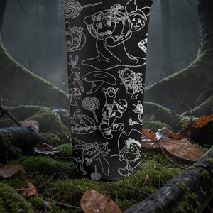 May include: Black tumbler with white line drawings of Halloween characters and items. The design includes pumpkins, lollipops, and cartoon figures. The tumbler is cylindrical.