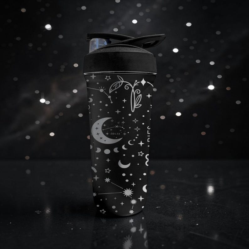 Pode incluir: Garrafa de &aacute;gua preta com tampa preta e design celestial. A garrafa apresenta ilustra&ccedil;&otilde;es brancas de luas, estrelas, constela&ccedil;&otilde;es e elementos bot&acirc;nicos. O design est&aacute; em um fundo preto.
