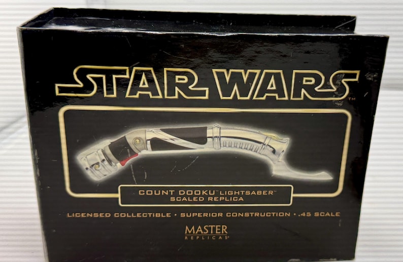 Puede incluir: Caja negra con el logo de Star Wars en dorado. Muestra una r&eacute;plica a escala del sable de luz del Conde Dooku. El sable de luz tiene un mango plateado y negro con detalles rojos. La caja indica "Coleccionable con licencia".