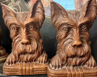 May include: A pair of wooden bookends shaped like Scottish Terriers. The bookends are brown and have a realistic, detailed design.