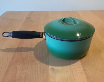 May include: Green enamel saucepan with a black handle and a matching lid. The saucepan has a white interior and a black rim.