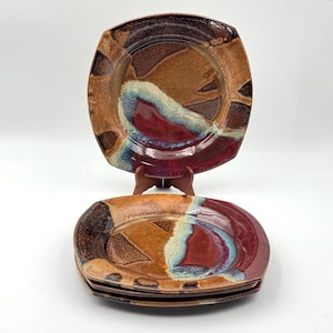 May include: A white ceramic mug with a black handle and the text "But First, Coffee" in a black, handwritten-style font. The mug is on a white surface.