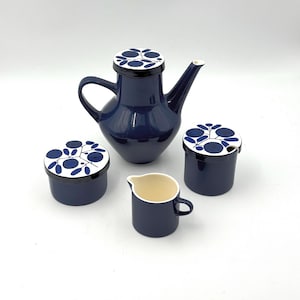 May include: A navy blue ceramic tea set with a floral design. The set includes a teapot, two covered containers, and a small creamer. The lids and containers have a white background with blue floral patterns.