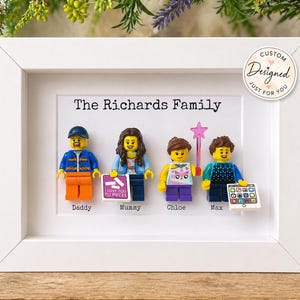 May include: A white framed display featuring four plastic minifigures representing The Richards Family. The figures are labeled Daddy, Mummy, Chloe, and Max. Accessories include a pink star wand, a tablet, and a sign reading I Love You To Pieces.