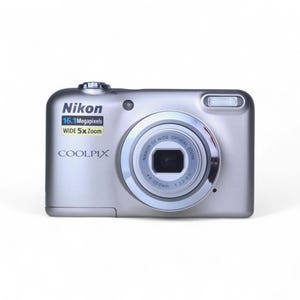 May include: Silver Nikon Coolpix digital camera with a 16.1-megapixel resolution and a wide 5x zoom lens. The camera has a built-in flash and a lens with the text "NIKKOR 5X WIDE OPTICAL ZOOM". The camera also has the text "COOLPIX".