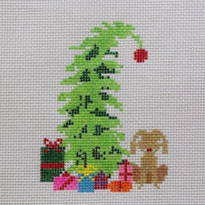 Op de afbeelding: Kruissteekontwerp met een groene kerstboom met een rode bal, omringd door ingepakte cadeaus in verschillende kleuren. Een bruine hond zit naast de cadeaus, allemaal op een lichtgrijze achtergrond. Feestelijk vakantiethema.
